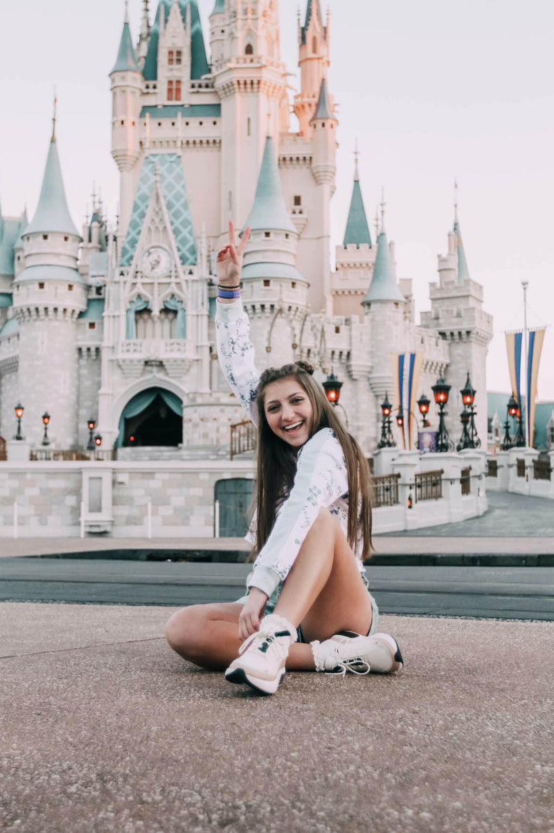 bright preset after photo of a girl sitting in front of a Disney castle
