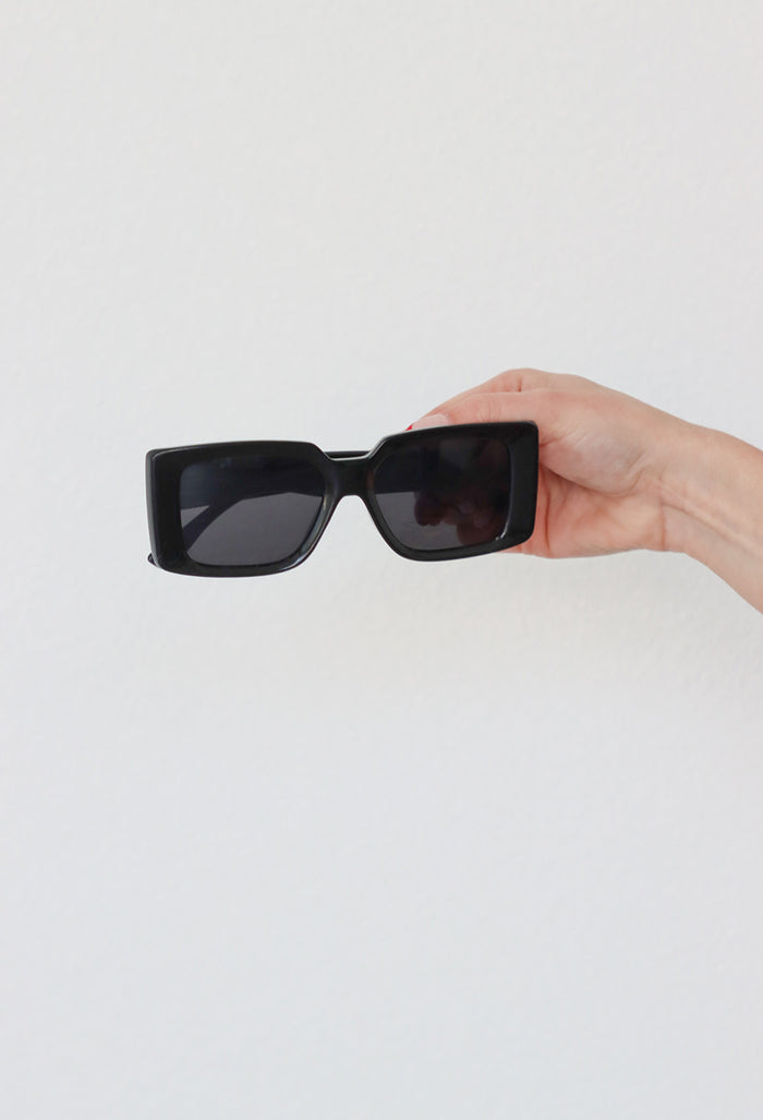 black sunglasses against a white wall
